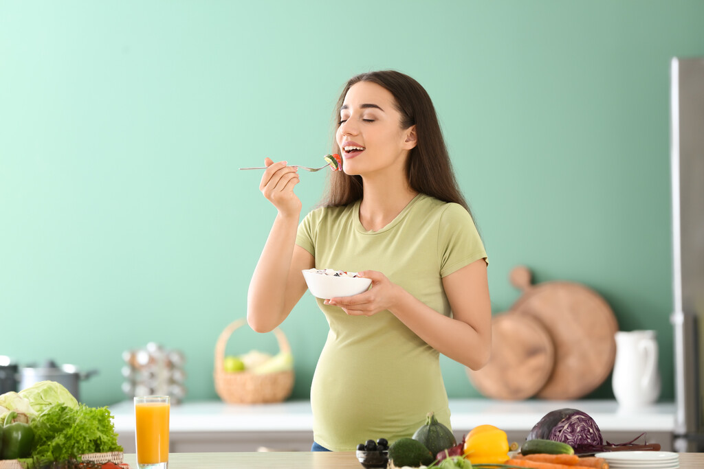 Grávida comendo alimentos com vitaminas para gestantes