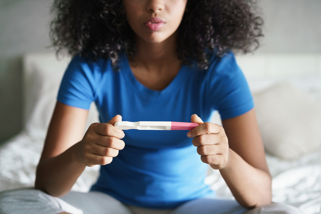 Mulher feliz com resultado do teste de gravidez na mão após entender como fazer o teste de gravidez